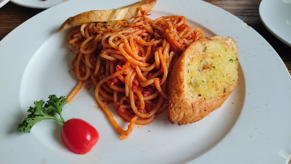 Spaghetti bolognese na białym talerzu z dwiema grzankami
